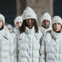 Grupa osób w białych kurtkach i czapkach Moncler. To właśnie moncler co to za firma – marka znana z luksusowej odzieży zimowej.