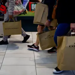 Ludzie z torbami na zakupy, w tym z torbami marki COACH. Udane zakupy w firmie, która oferuje stylowe produkty.