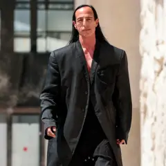 Rick Owens, w charakterystycznym czarnym płaszczu, idzie pewnym krokiem.