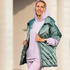Kobieta w pastelowej bluzie i spodniach, z pikowaną kurtką w odcieniu miętowym. Idealna stylizacja, która pokazuje, jaka kurtka do dzwonów pasuje.