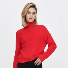 Kobieta w czerwonym swetrze z golfem i czarnych spodniach na białym tle.