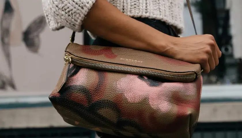 Torba Burberry z motywem moro, przykład brytyjskich marek odzieżowych, noszona przez kobietę w swetrze.