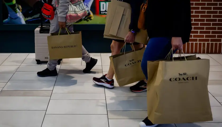 Ludzie z torbami na zakupy, w tym z torbami marki COACH. Udane zakupy w firmie, która oferuje stylowe produkty.