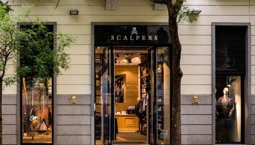 Elegancki sklep Scalpers, hiszpańska firma odzieżowa, z witrynami pełnymi ubrań i manekinami w garniturach.