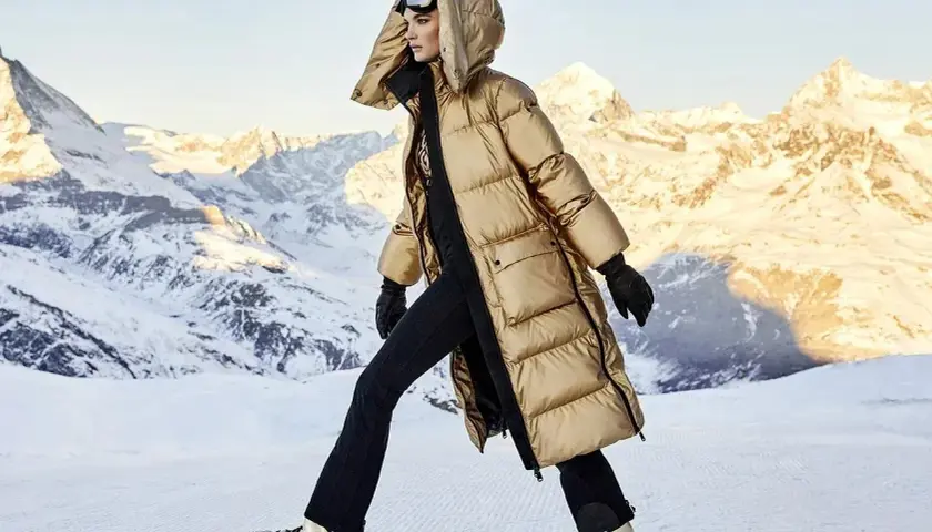 Modelka w złotej kurtce i goglach narciarskich, gotowa na après-ski w górach.
