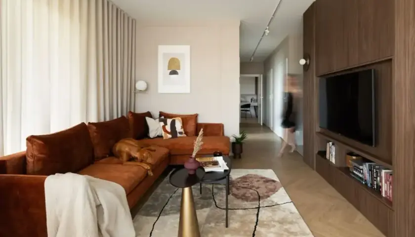 Nowoczesny salon z brązową kanapą i czarnymi akcentami. Pies odpoczywa na kanapie. Czy czarny pasuje do brązowego? Tak, tworzy elegancką całość.