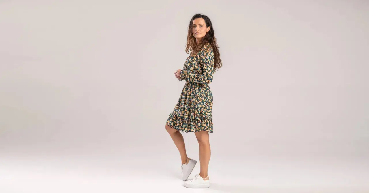 Kobieta w kwiecistej sukience i białych sneakersach. Czy sukienki w kwiaty są modne? Tak, ta stylizacja to dowód!