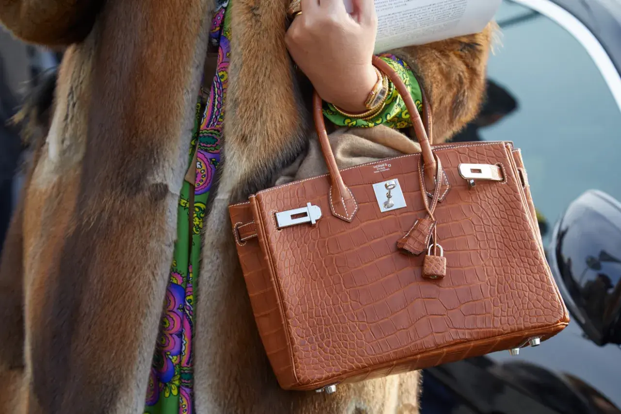Elegancka torebka marki Hermes w kolorze koniaku, wykonana ze skóry krokodyla, z charakterystycznym zapięciem i małą kłódką.