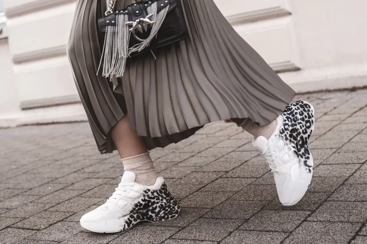 Białe sneakersy w panterkę i beżowe skarpetki to idealne buty do spódnicy. Stylowy dodatek do każdej stylizacji.