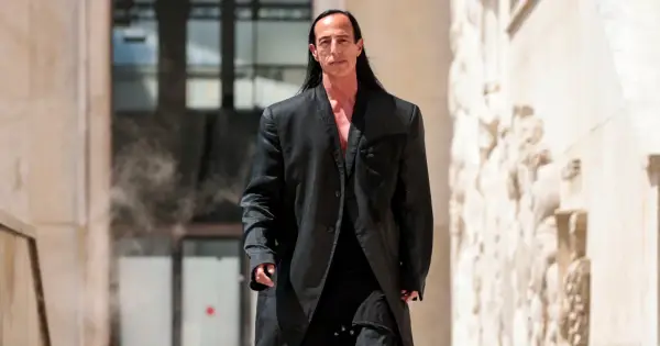 Rick Owens, w charakterystycznym czarnym płaszczu, idzie pewnym krokiem.